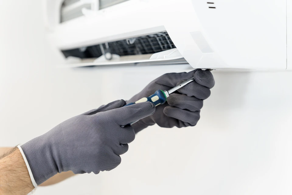 Femme professionnelle souriante en costume gris et casque de chantier bleu, bras croisés dans un bâtiment en construction ou rénovation