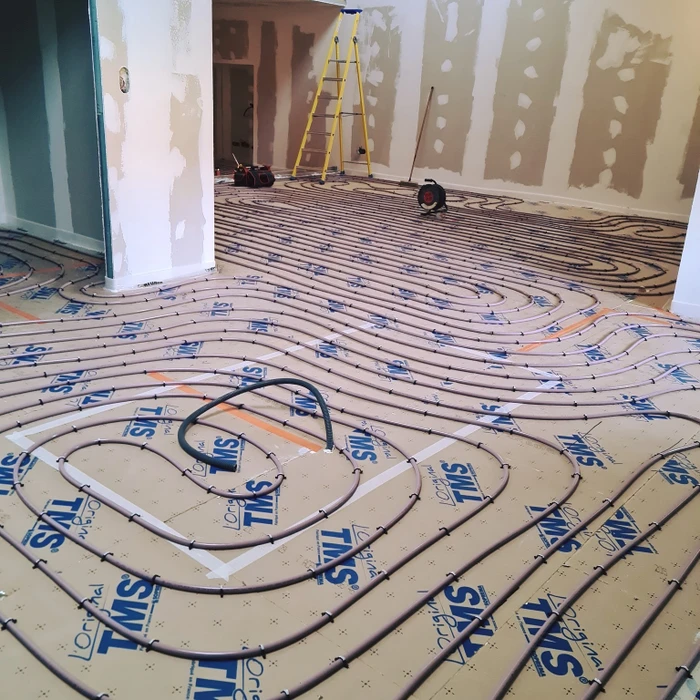 Scène d'incendie domestique montrant un câble électrique en feu branché dans une prise murale, dégageant fumée et flammes sur mur blanc intérieur