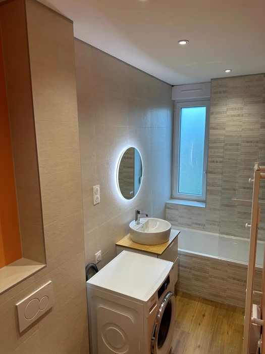 Table basse en métal, fauteuil gris, canapé blanc avec couverture et oreiller, grand tableau sur le mur bleu dans un intérieur de salon