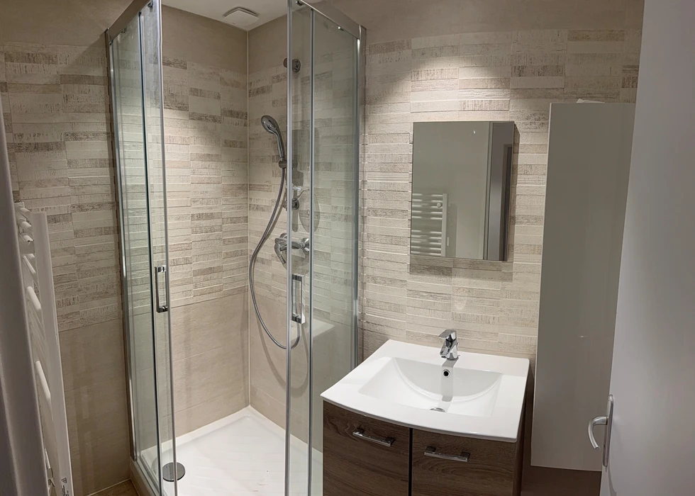 Salle de bains moderne avec baignoire encastrée, vasque rectangulaire blanche sur meuble bois, robinetterie noire mate